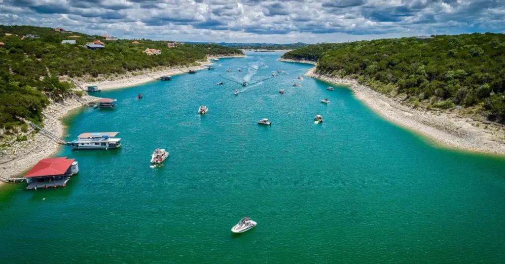 Aerial view of a Lake Travis cove with boats moored to a floating boathouse, the kind of floating dock setup most Hill Country waterfront properties end up choosing.