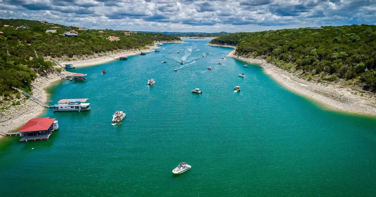 Aerial view of a Lake Travis cove with boats moored to a floating boathouse, the kind of floating dock setup most Hill Country waterfront properties end up choosing.