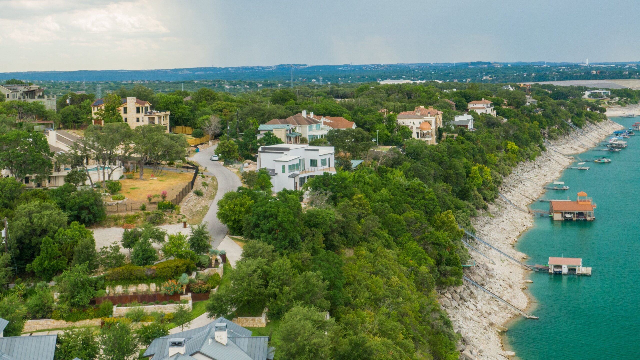 Aerial view of Hill Country waterfront homes terraced into Lake Travis shoreline, illustrating the slope and rocky soil that drive retaining wall construction in Austin.